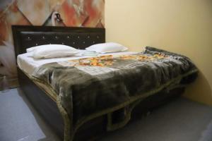 Ce lit se trouve dans un dortoir doté d'un couvre-lit noir. dans l'établissement OYO Hotel Grand AB, à Meerut