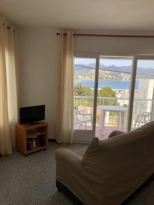sala de estar con sofá, TV y balcón en Espectaculares vistas al mar Ático y apart 3 habitaciones, en Llançà