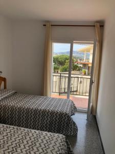 リャンサにあるEspectaculares vistas al mar Ático y apart 3 habitacionesのベッド2台とガラスのスライドドアが備わるホテルルームです。