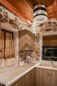 a kitchen with a stone wall and a chandelier at Tramonto Villa in Lagoúdi Zía