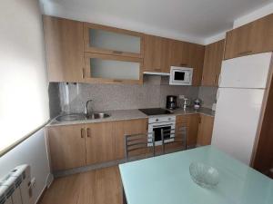 a kitchen with wooden cabinets and a white refrigerator at Apartamento Laura in O Pindo