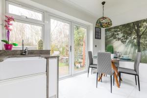 a kitchen with a table and chairs and a window at Relaxing Park Side Bungalow in Romford