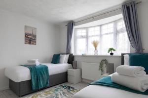 a bedroom with two beds and a window at Relaxing Park Side Bungalow in Romford