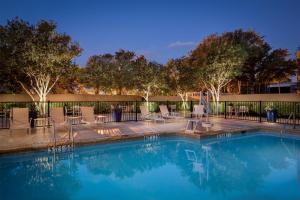 a swimming pool with chairs and a fence at Sheraton DFW Airport Hotel in Irving