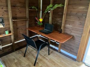 un ordinateur portable assis sur une table en bois avec une chaise dans l'établissement Nature et quiétude, à Le Moule
