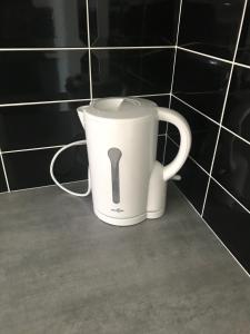 a white coffee cup sitting in a bathroom at residence julius aéroport tillé classé 3 étoiles in Tillé
