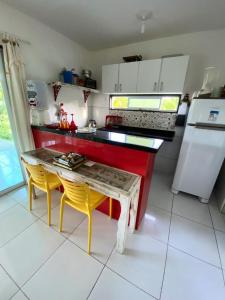 een keuken met een tafel en 2 gele stoelen bij Ville Santorinni in Japaratinga
