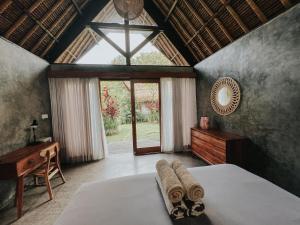 a bedroom with a bed and a desk and a window at Villa Amantes Bingin in Uluwatu