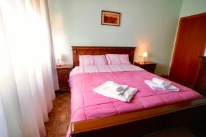 una camera da letto con un letto rosa e asciugamani di Affittacamere Umberto&Marisa a Foligno