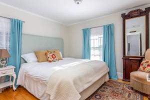a bedroom with a bed with blue curtains and a mirror at SeaCity View in Swampscott