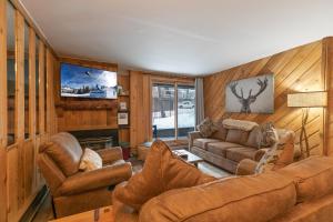 ein Wohnzimmer mit einem Sofa, Stühlen und einem TV in der Unterkunft Trails End Starry Night Condo - Downtown Breck, Ski In-Out in Breckenridge