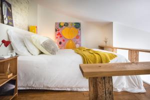 a bedroom with a white bed with a painting on the wall at LE SECRET in Saint-Martin-de-Ré