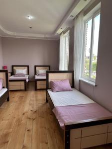 three beds in a room with wooden floors and windows at Guesthouse TEA in Kutaisi