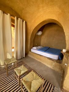 a bedroom with a bed and chairs in a cave at Lala Land Camp in Nuweiba