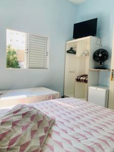 a bedroom with two beds and a flat screen tv at Hotel Planalto in Poços de Caldas