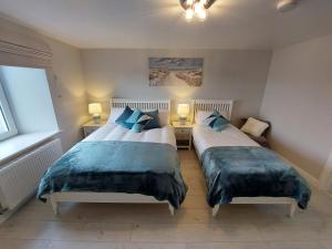 2 letti in una piccola camera da letto con 2 lampade di Costa Glebe a Dungloe