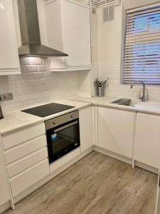 a kitchen with white cabinets and a sink and an oven at 1 bed apartment in Zone 2, minutes from Oval tube. in London