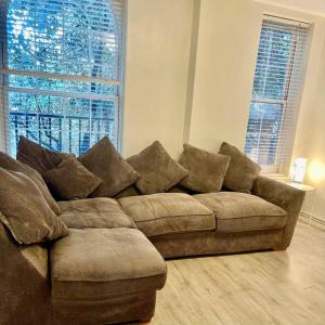a brown couch in a living room with two windows at 1 bed apartment in Zone 2, minutes from Oval tube. in London