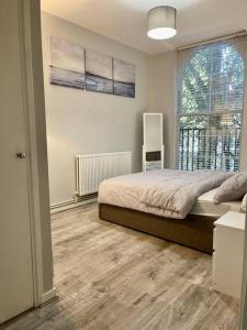 a bedroom with a bed and a large window at 1 bed apartment in Zone 2, minutes from Oval tube. in London