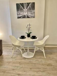 ein weißer Tisch mit 2 Stühlen und ein Tisch mit Blumen in der Unterkunft 1 bed apartment in Zone 2, minutes from Oval tube. in London