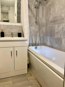a bathroom with a white tub and a sink at 1 bed apartment in Zone 2, minutes from Oval tube. in London