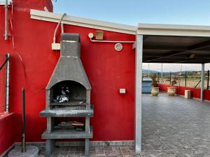 un bâtiment rouge avec un four à pizza sur le côté dans l'établissement Casa Vacanze Marina di Ragusa Il Gufo e La Civetta apt, à Marina di Ragusa