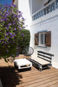 a patio with a bench and a bush with purple flowers at Casa Boa Onda in Sagres