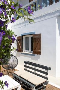 a bench sitting in front of a window with purple flowers at Casa Boa Onda in Sagres
