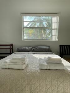 a bed with white towels on it with a window at Queen's Tropical Garden View Room in Palmetto Bay