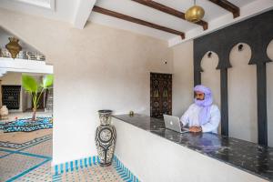 a person sitting at a counter with a laptop at Riad Jouba in Merzouga