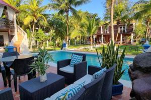 een patio met stoelen en een zwembad met palmbomen bij Huellas en la arena Casa De Playa in Tela