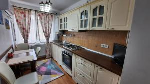 cocina con armarios blancos, mesa y fogones en Apartament Centru, en Cugir