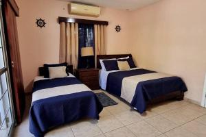 1 dormitorio con 2 camas con sábanas azules y blancas en Huellas en la arena Casa De Playa, en Tela