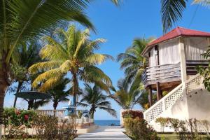 a house on the beach with palm trees and the ocean at Huellas en la arena Casa De Playa in Tela