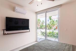 a bedroom with a flat screen tv on a wall at Ground level Garden condo at Akumal south by TAO Santamar in Akumal