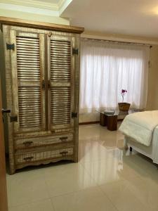 ein Schlafzimmer mit einem Bett und einem großen Fenster in der Unterkunft Pousada. Espatódea in Petrópolis