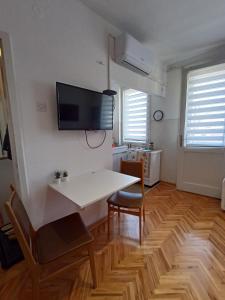uma sala de estar com uma mesa e uma televisão na parede em Apartman Natalija em Kuršumlija
