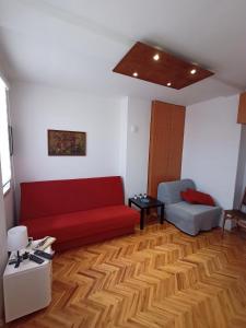 Apartman Natalija في Kuršumlija: غرفة معيشة مع أريكة حمراء وكرسي