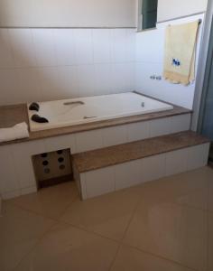 a white bathroom with a tub and a sink at Pousada residencial in Curvelo