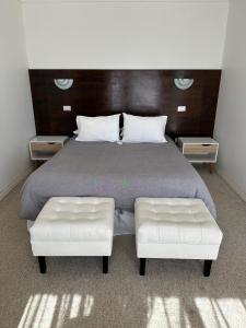 a bedroom with a bed with two white leather seats at American Hotel in Los Vilos