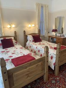 a bedroom with two beds with red pillows on them at Knighton Lodge in Skegness