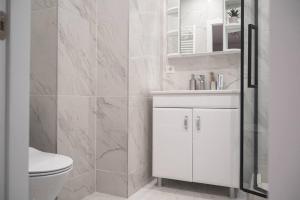a white bathroom with a toilet and a sink at RentWill apartments Sixteen in Chişinău