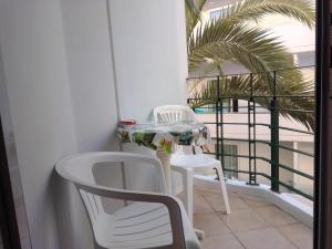 a balcony with two white chairs and a table and chairs at GT Apartment in Rhodes Town