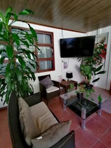a living room with a couch and a tv at Airport Traveler's home. in Alajuela