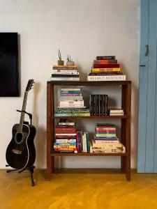 a book shelf filled with books and a guitar at Minha Casa em Caraíva in Caraíva