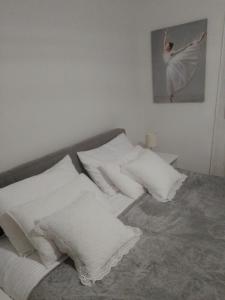 - un lit avec des oreillers blancs et une photo sur le mur dans l'établissement Nektar 88, à Vrnjačka Banja