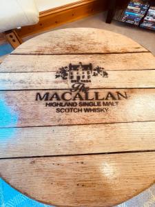 une table en bois circulaire avec un panneau en haut dans l'établissement Macallen, à Nairn