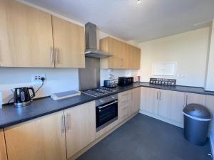 a kitchen with wooden cabinets and black counter tops at Cliff Haven, Sea View Holiday Home. in Cullercoats