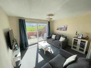 a living room with a couch and a window at Cliff Haven, Sea View Holiday Home. in Cullercoats