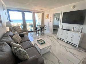 sala de estar con sofá y TV de pantalla plana en Island Winds East 202 by ALBVR - Beautifully renovated beachfront condo & steps away from Hangout & more!, en Gulf Shores